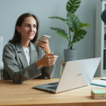 lady holding phone while working on a laptop